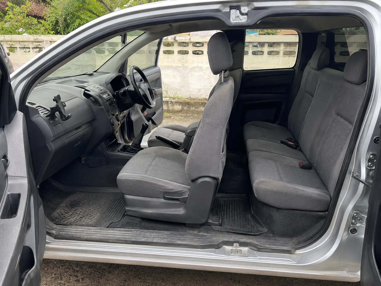 The cabin of a used pickup — worn but honest: a fabric seat with light bolster wear, a clean dash, an aftermarket phone mount.